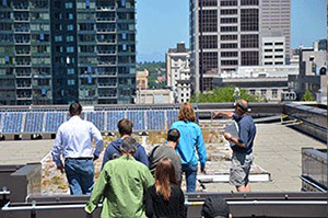 People on building roof examining solar panels
